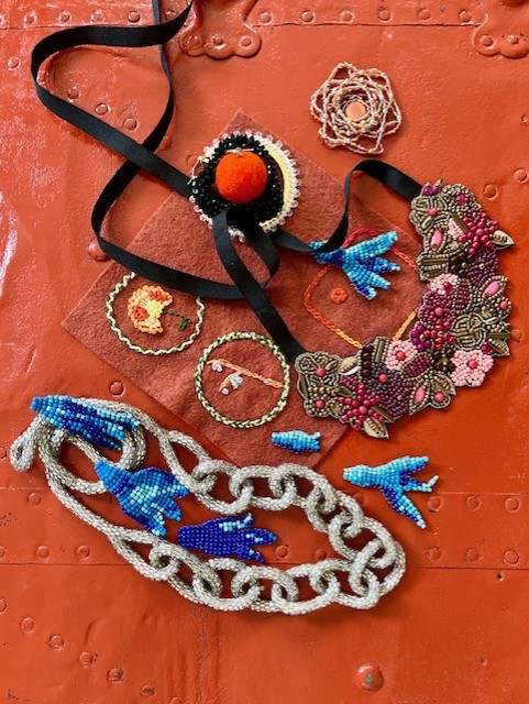 A variety of necklaces, bracelets, earrings, and other beaded pieces laying on top of a bright red steamer trunk.