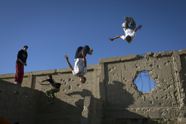 children jumping near broken wall