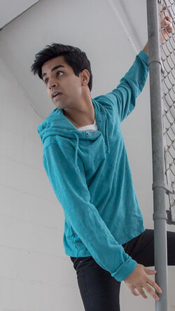 Image of Taha Mandviwala doing parkour exercise off of a metal fence wearing a teal sweatshirt