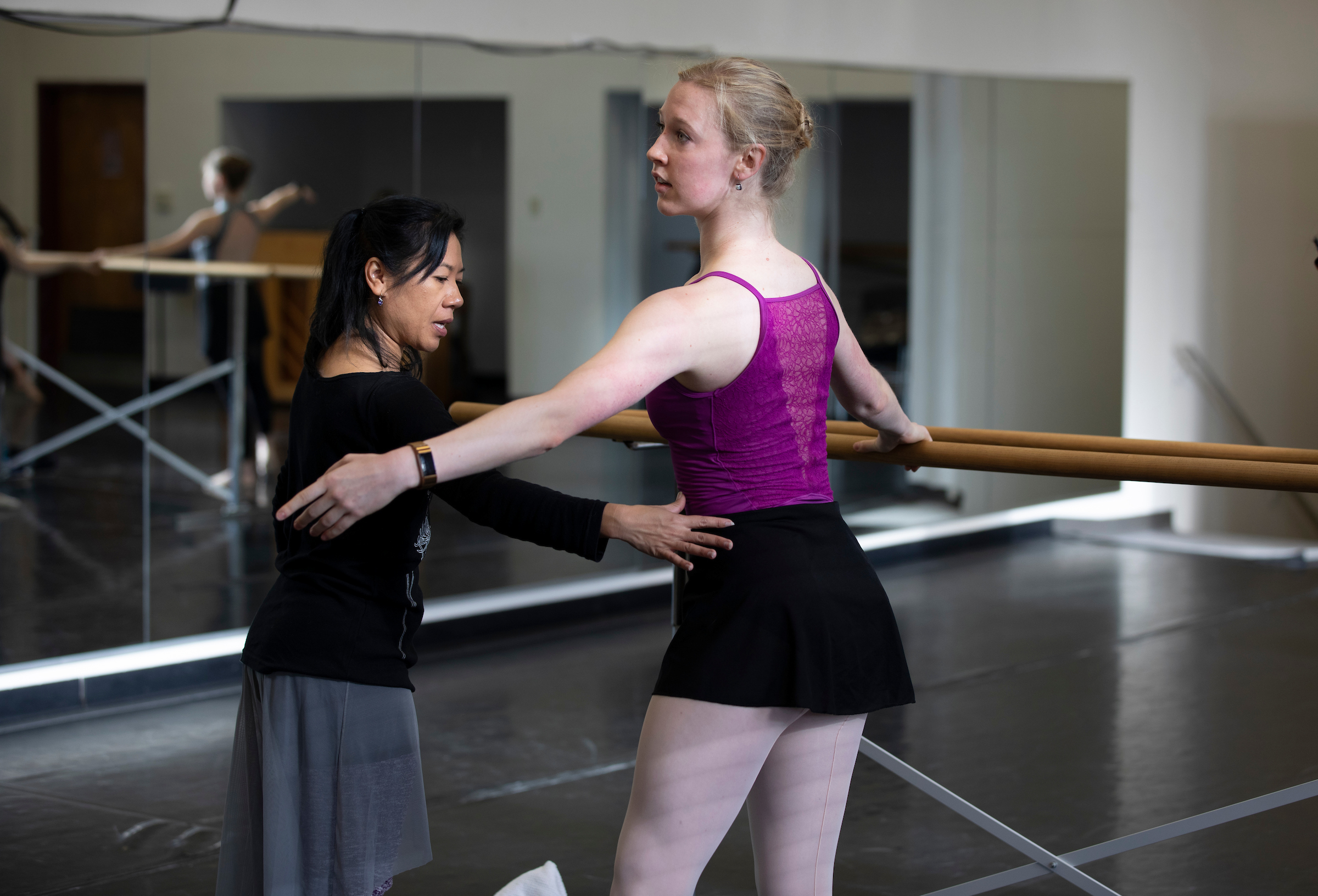 dancer at barre with instructor giving feedback