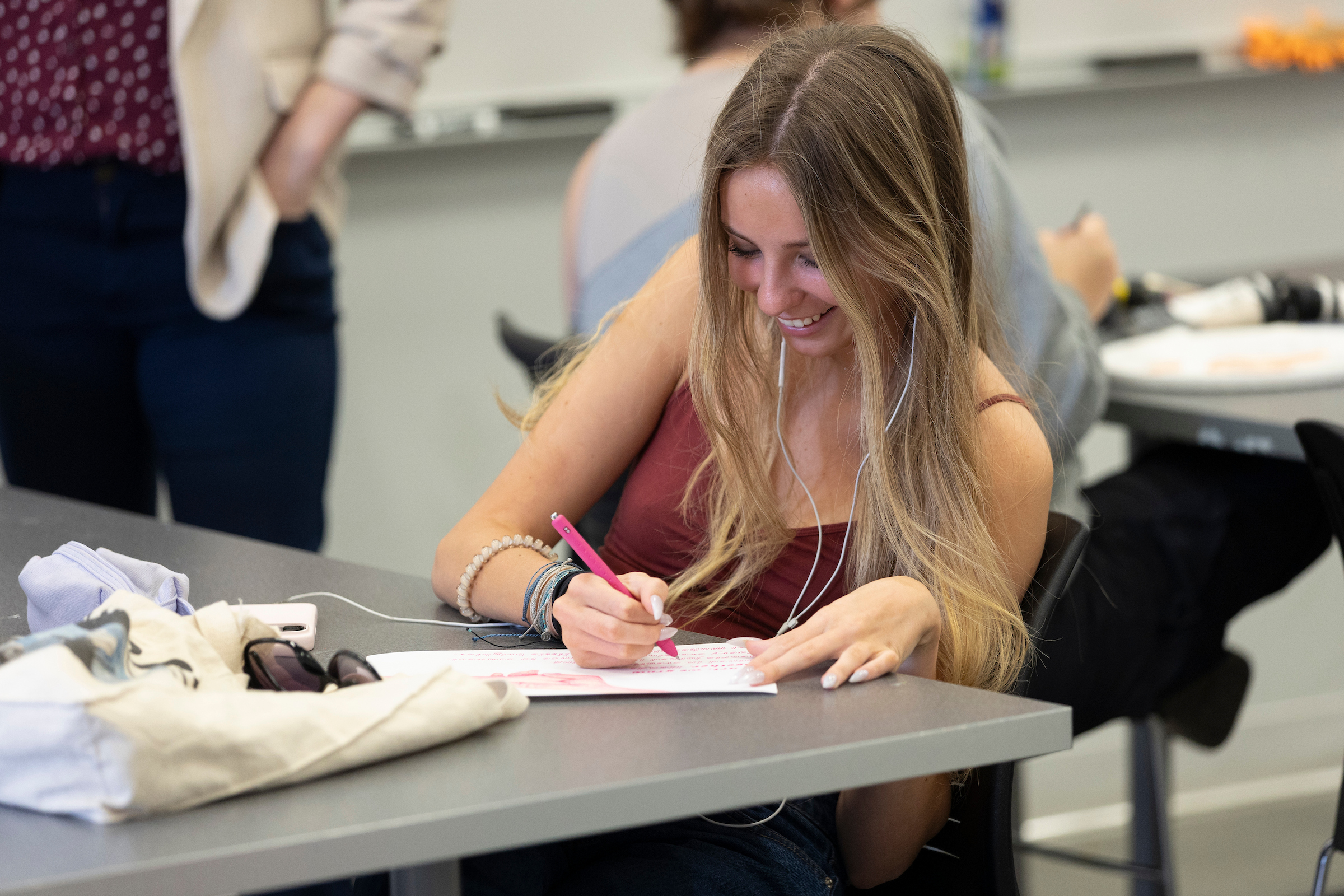 student writing on paper smiling