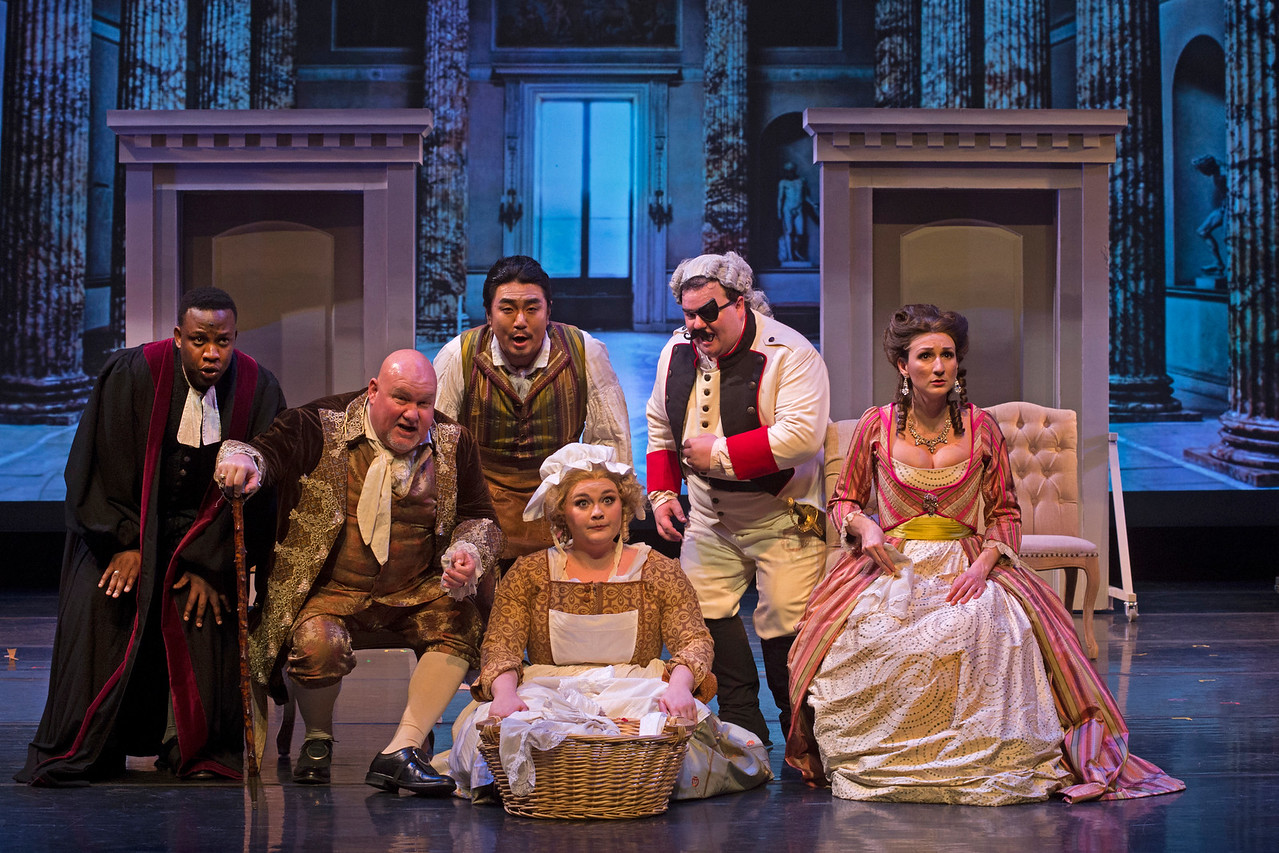 Production still of UK Opera Theatre's "Barber of Seville" with cast onstage in period dress