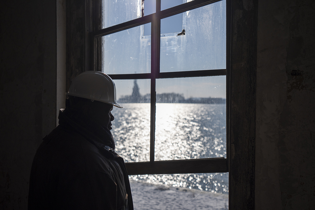 Everett McCorvey profile looking out window at Statue of Liberty