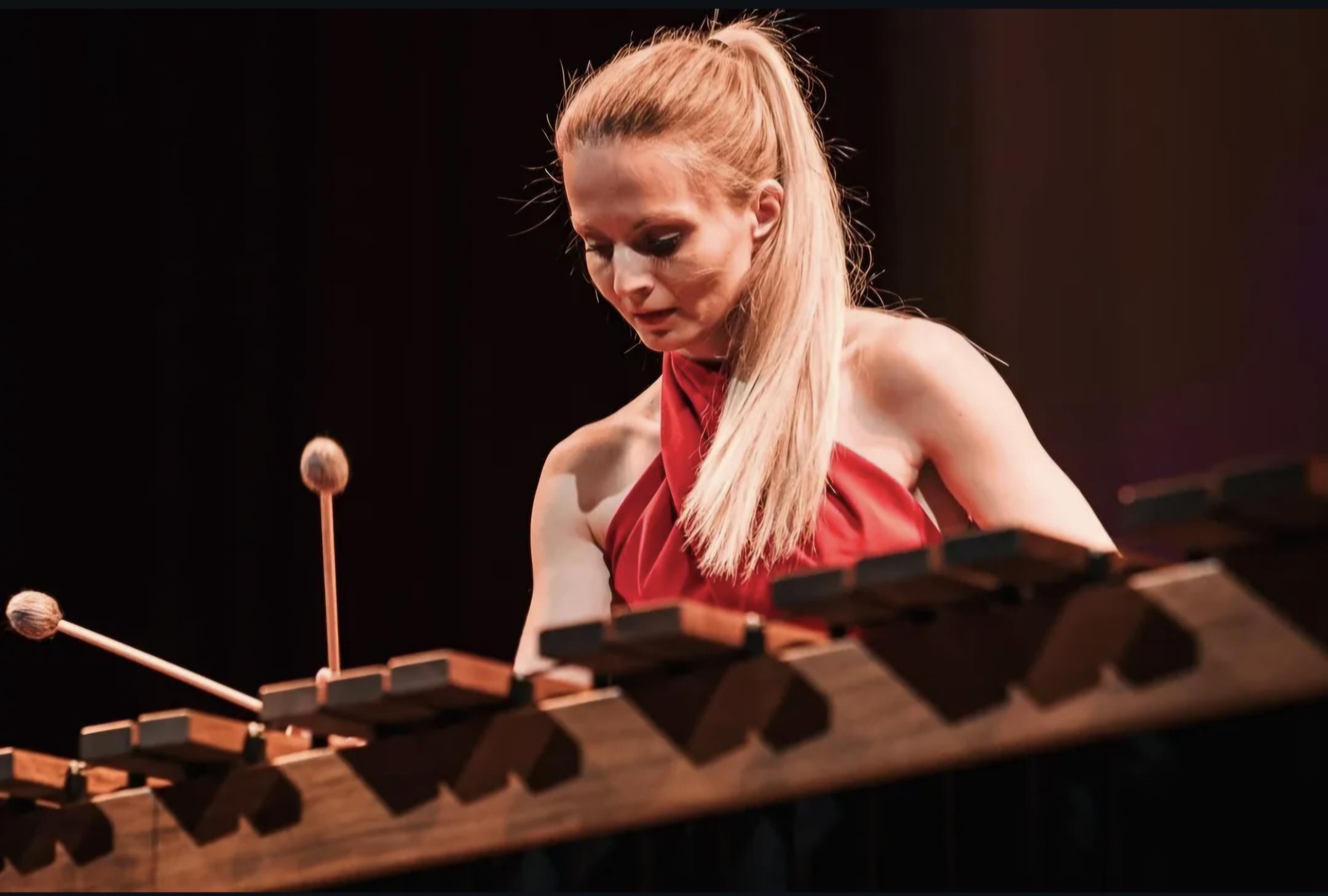 Nežka Prosenjak plays a xylophone, wearing a red top
