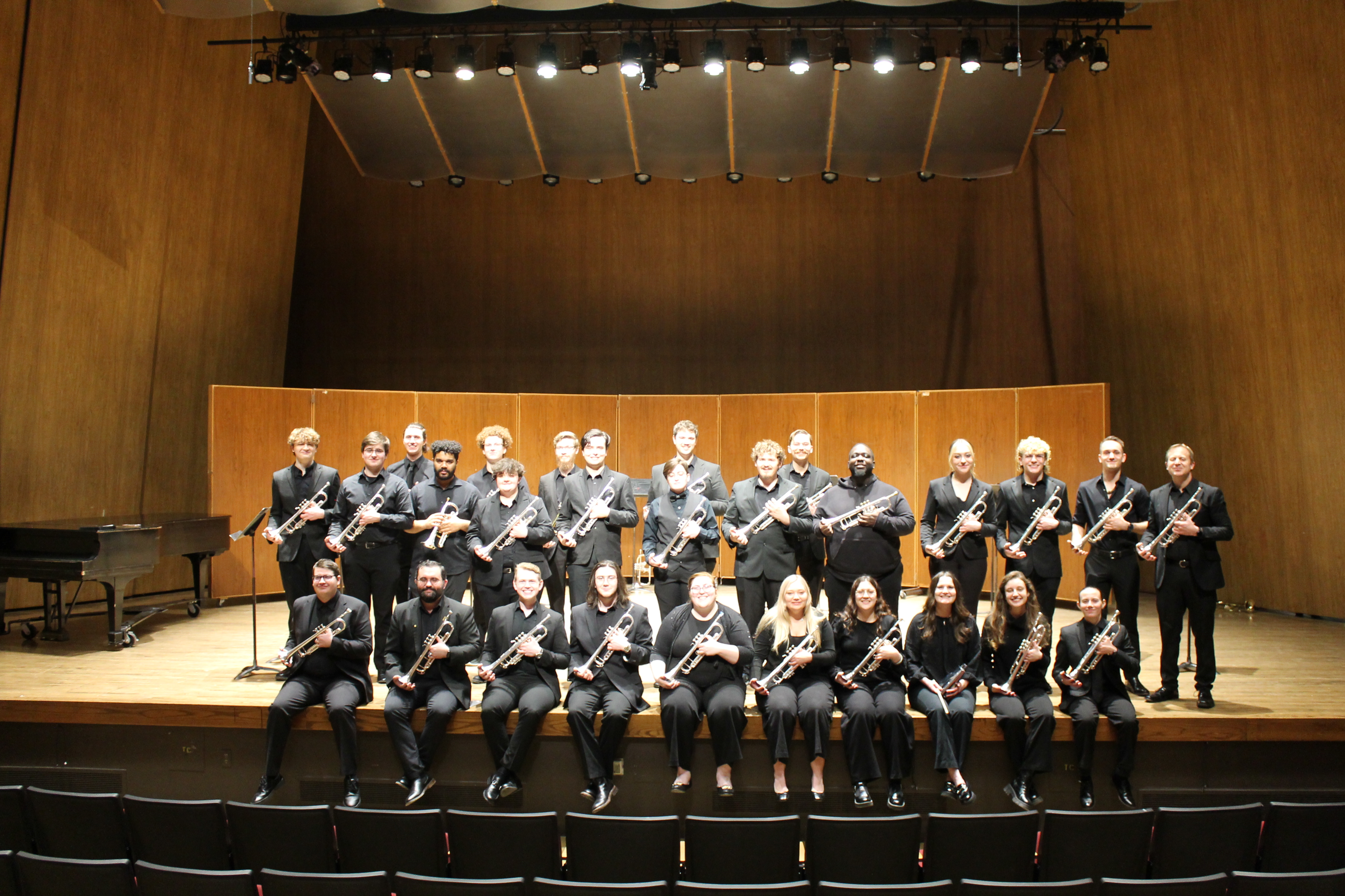 Members of the UK Trumpet Ensemble wearing black concert attire onstage holding their instruments