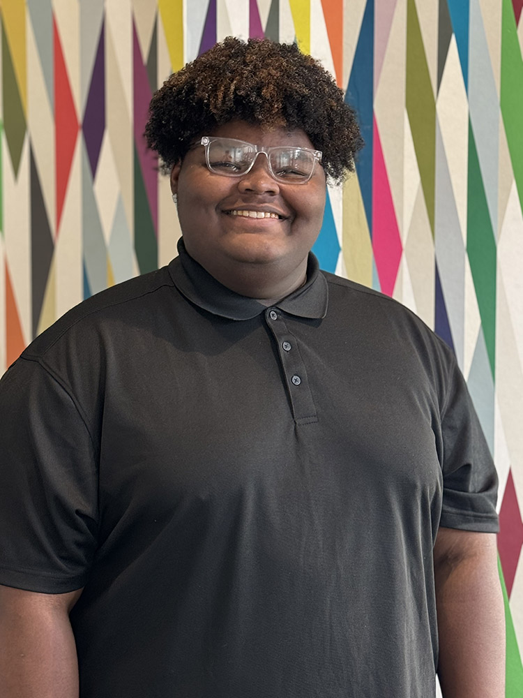 Peer Mentor Darian Wright stands in front of a colorfully painted geometric pattern.