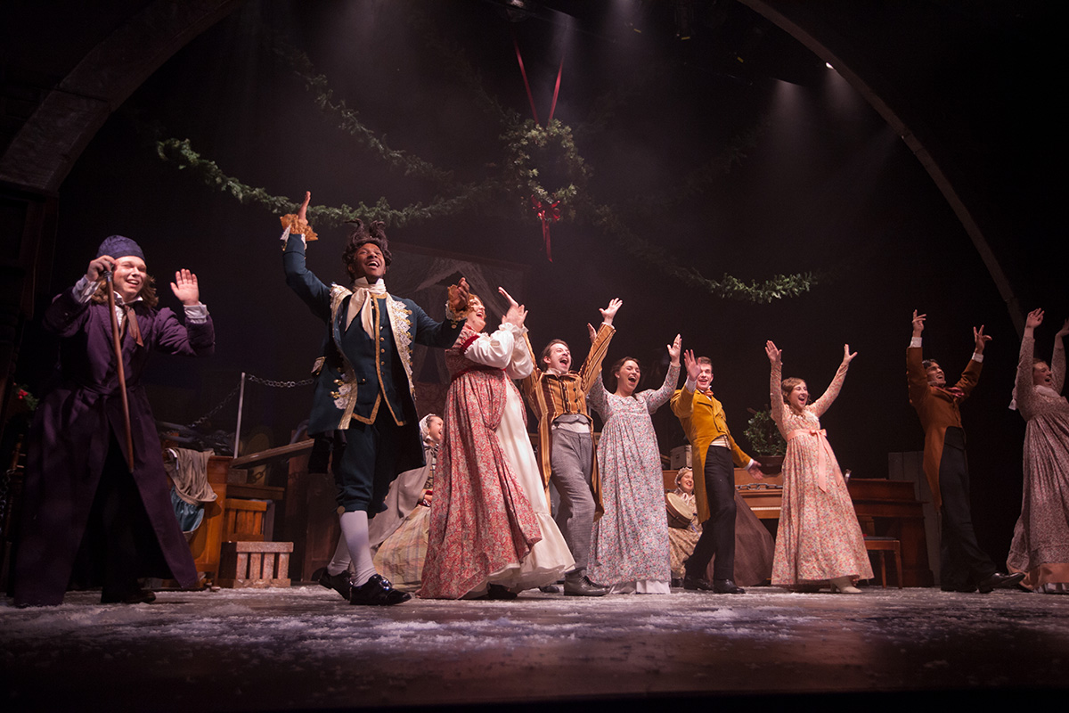 Several Actors in fantastical period dress during the past party scene in A Christmas Carol.