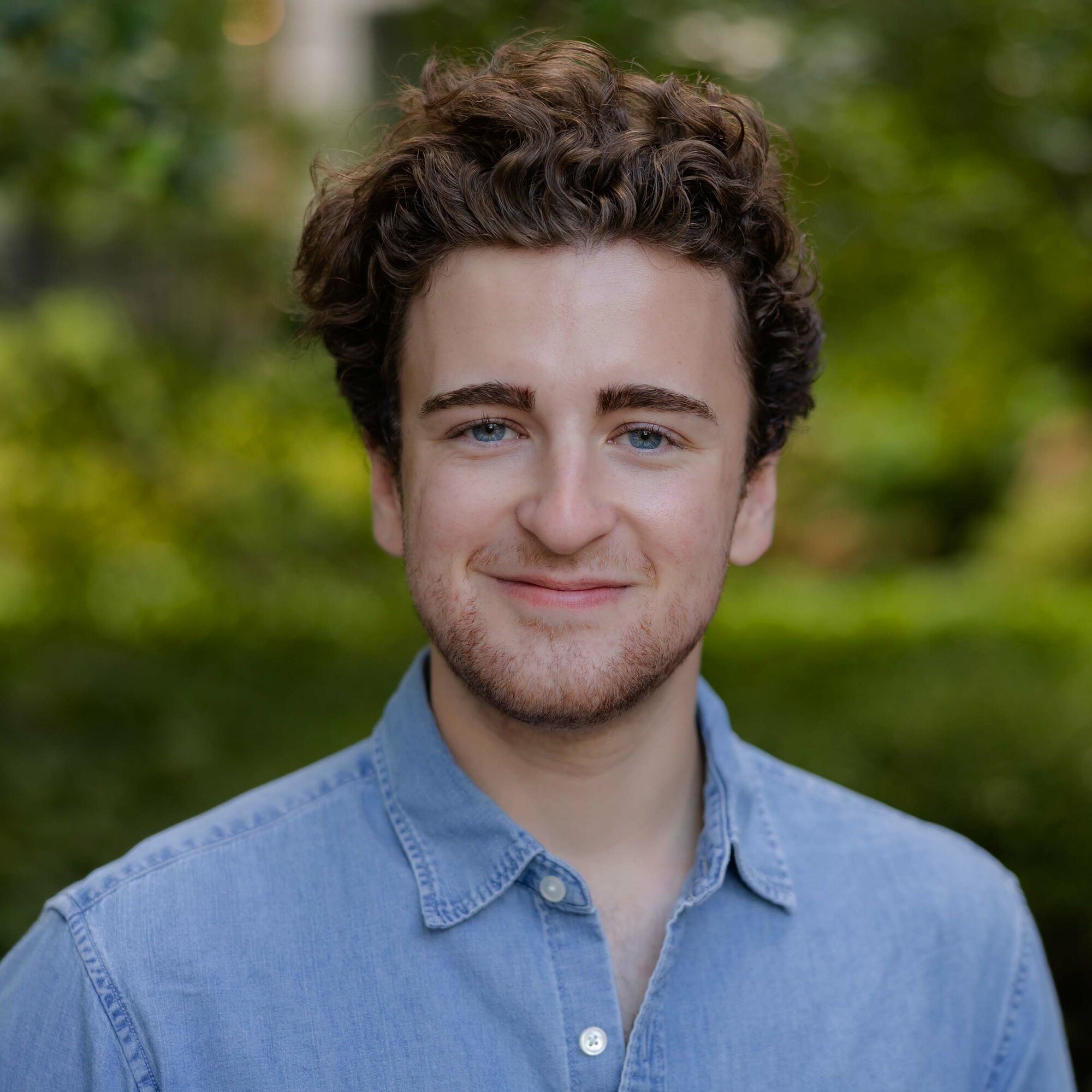 Image of Devin Landis wearing a blue button down against an external backdrop