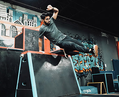 A man vaulting over the side of an obstacle set up on a stage.