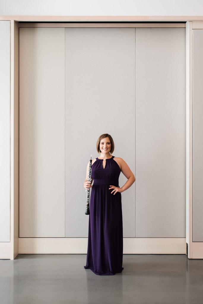 Image of Dr. ToniMarie Marchioni holding oboe in purple gown against white backdrop