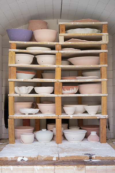 A multitude of glazed pots packed into a kiln before firing.