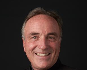 Headshot of Andy Collinsworth, smiling in front of a dark gray background.