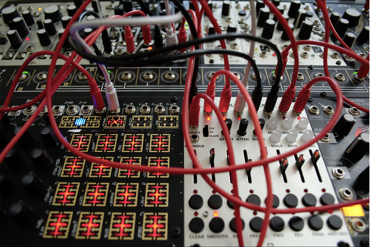 Close up on a professional mixer and soundboard with many red, white, and black crisscrossing wires.