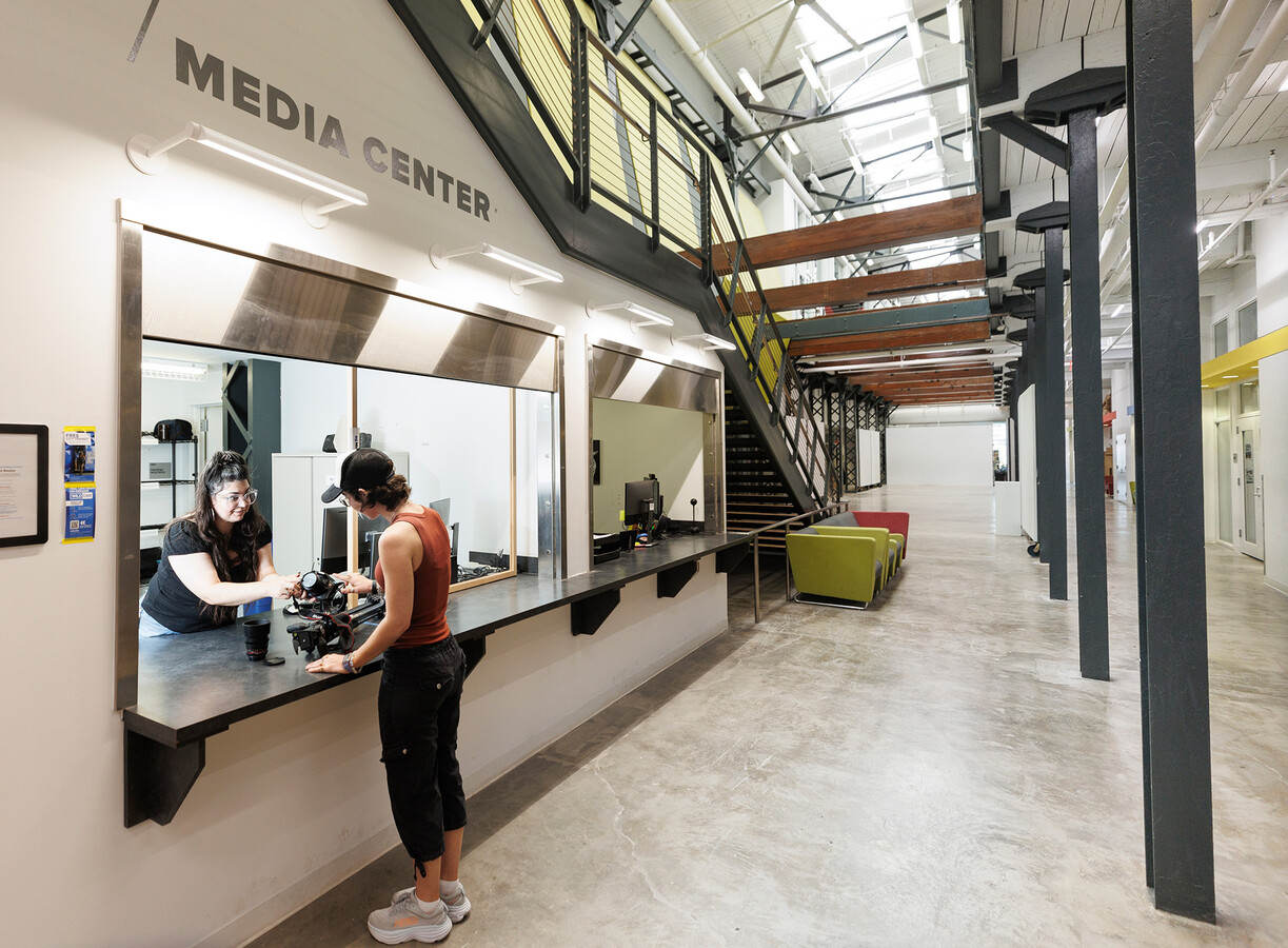 Media Center text on wall with two windows and staircase, two people