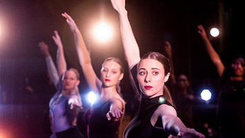 Dancers striking a pose in a row with stage lights.