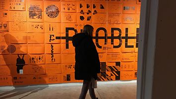 person walking across wall of orange images