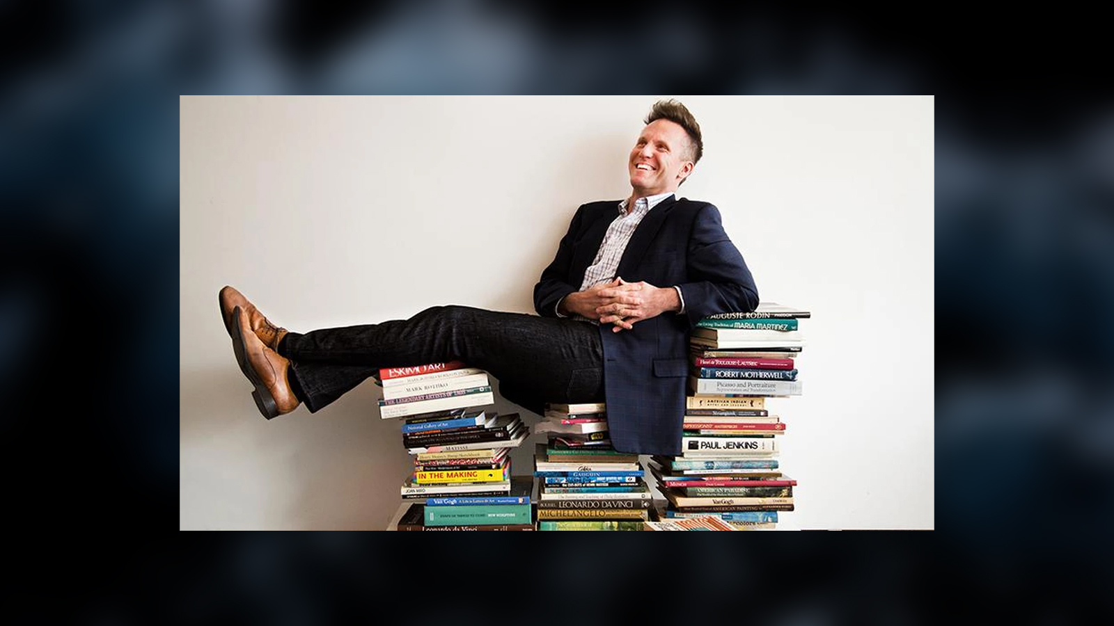 Image of Theo Edmonds reclining in a suit on a stack of books