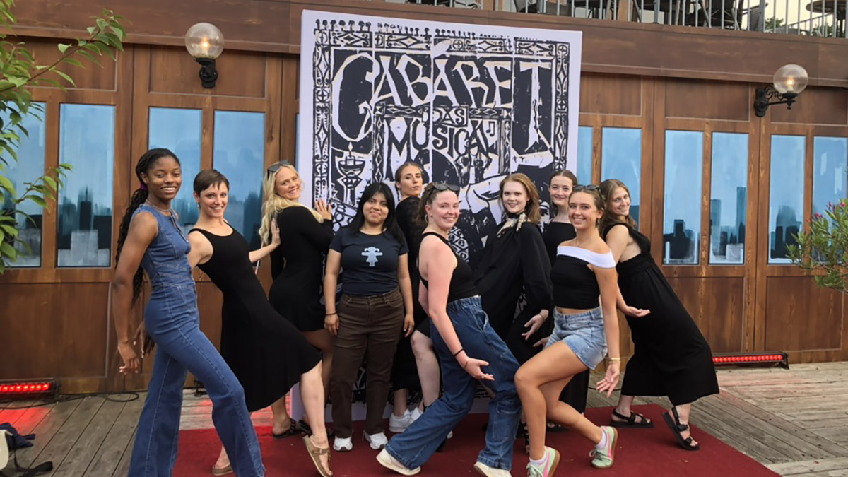 Dancers pose in front of Cabaret sign in Berlin Germany