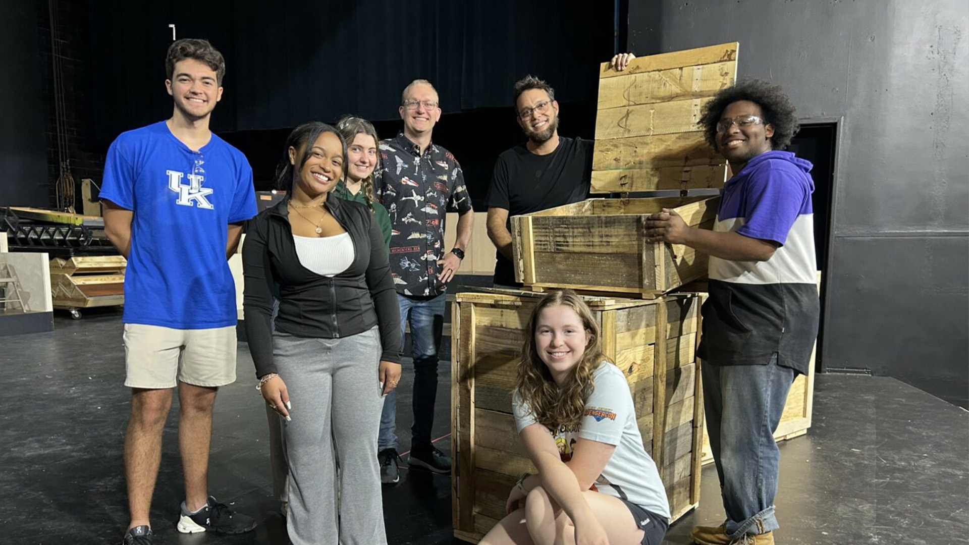 Department of Theatre and Dance Production Manager and Technical Director, Zack Stribling, joins students around a set piece onstage at the Guignol Theatre.
