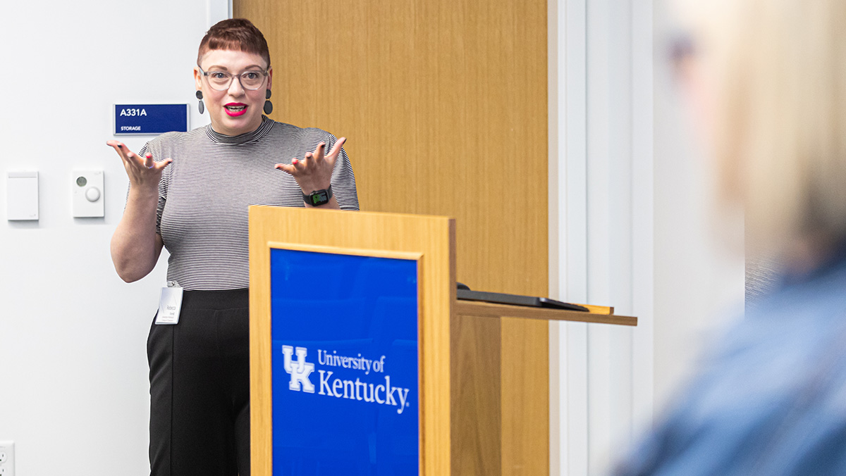 UK doctoral graduate Rebecca Ferrell beside a podium speaking at a symposium for women leaders in arts administration