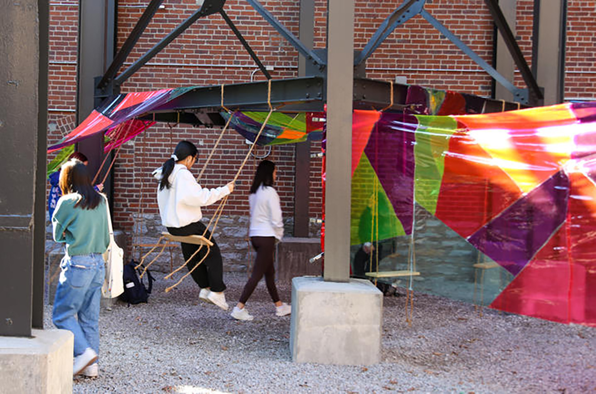 people swinging and colored fabric draped around urban landscape