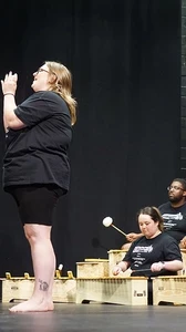 Some teachers playing xylophones while others play recorder and another group poses on stage.