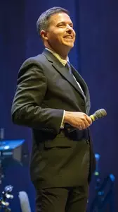 Matthew Gibson on stage holding a microphone