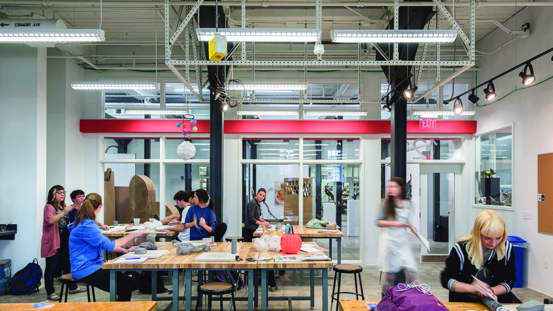 Foundations class in studio, many students working on projects throughout the open brightly lit space and large tables.