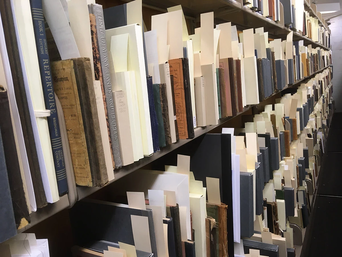 A bookstack in the library with many labeled an organized music books, manuscripts and documents.