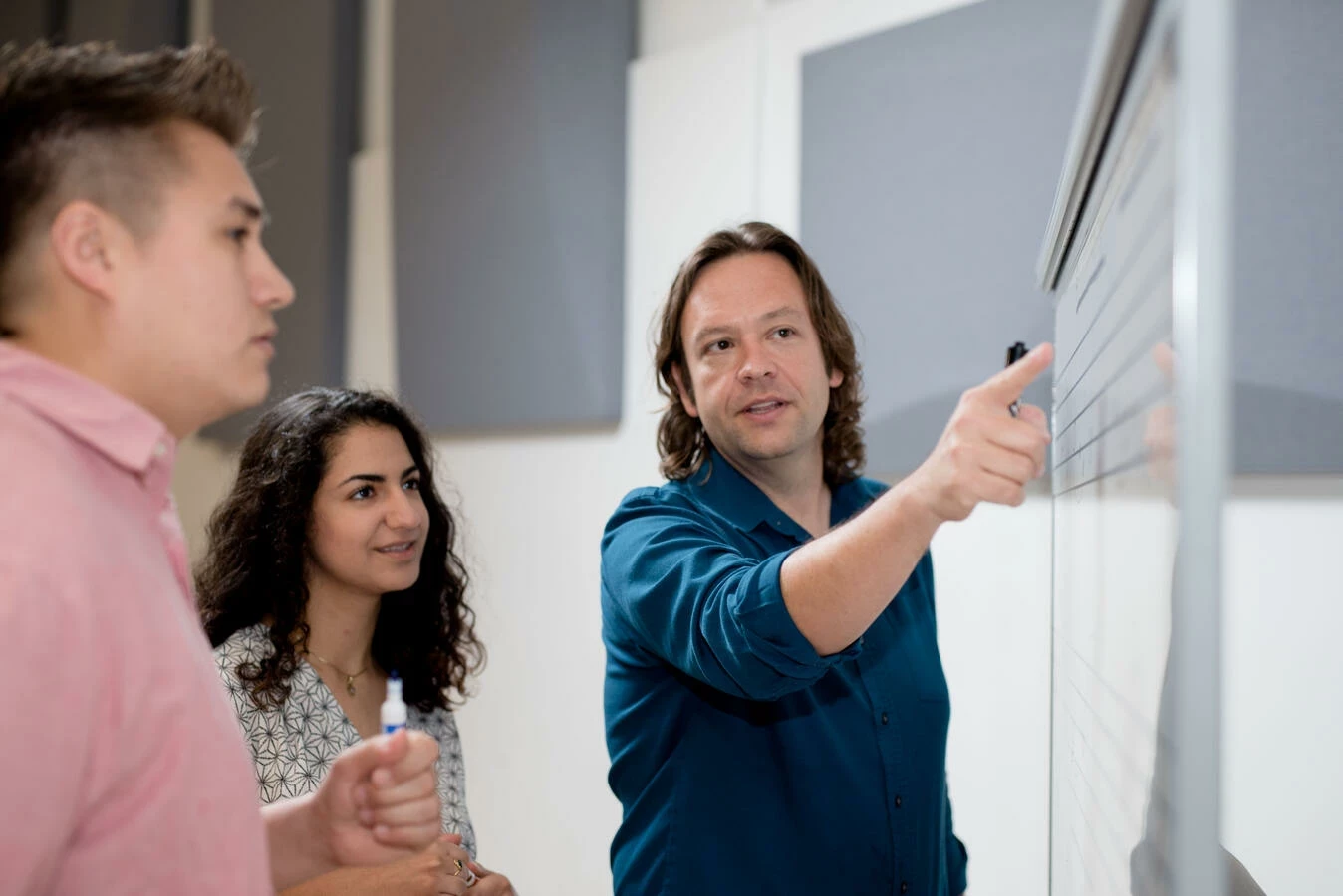 Instructor points at board with two students