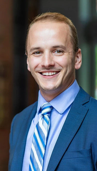 Headshot of Nick Johnson in a blue suit smiling at the camera.
