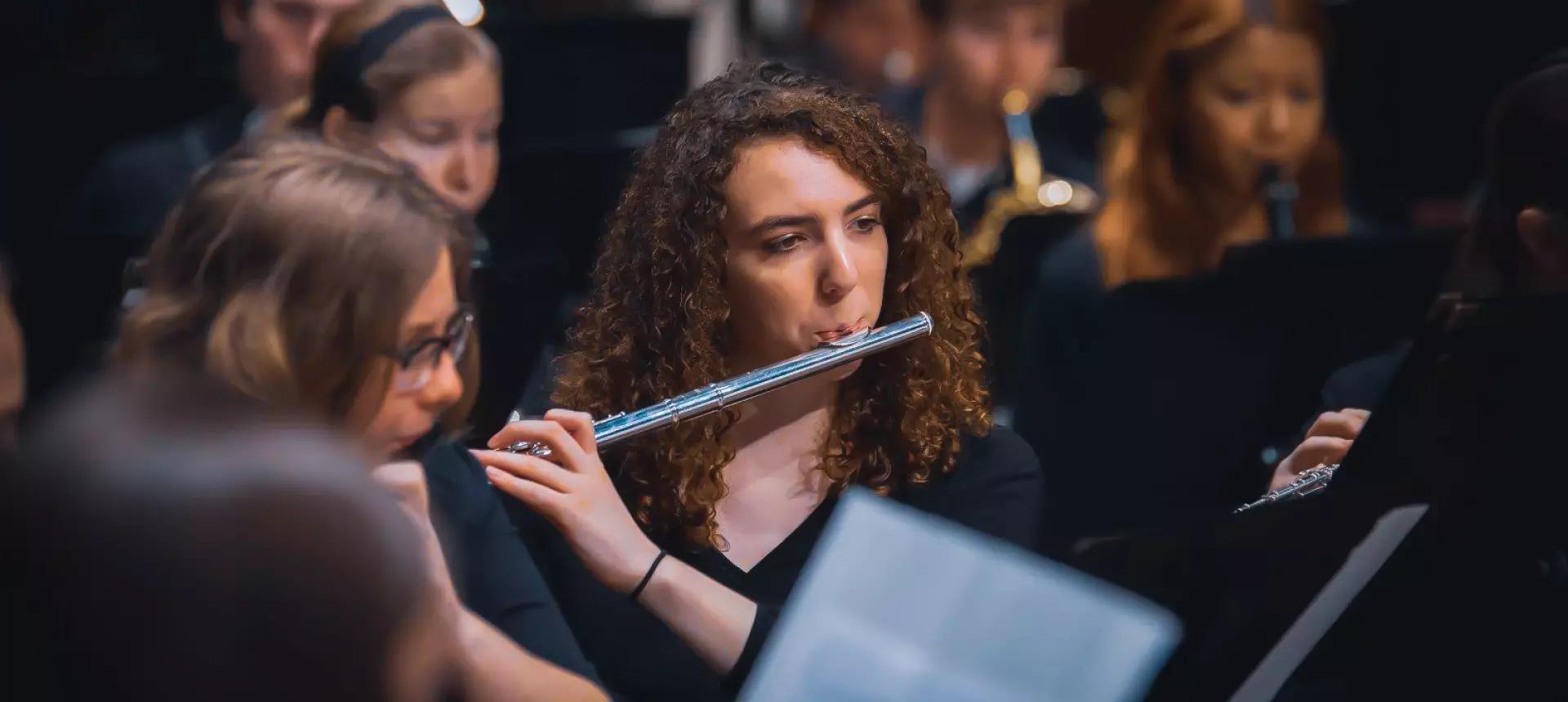 music student plays flute in orchestra on stage