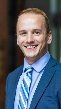 Headshot of Nick Johnson in a blue suit smiling at the camera.