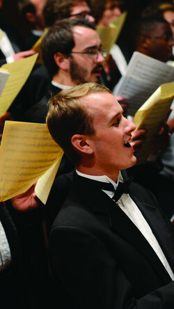 Image of men's chorus, singing in concert wearing tuxedos