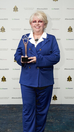 Image of Renee Cobb holding her Stevie Award, wearing a blue suit