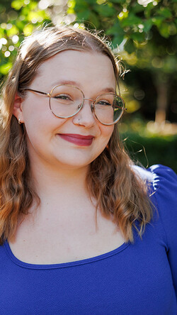 elizabeth watson smiling at camera with blurred trees background