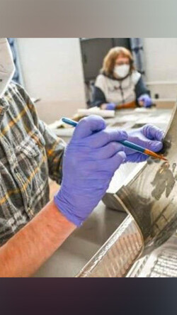 A volunteer at Hindman Settlement School helps restore a photograph following the massive Eastern Kentucky flood in July 2022. Flood waters irreparably damaged documents, photos and various works of art. Photo by Will Anderson.