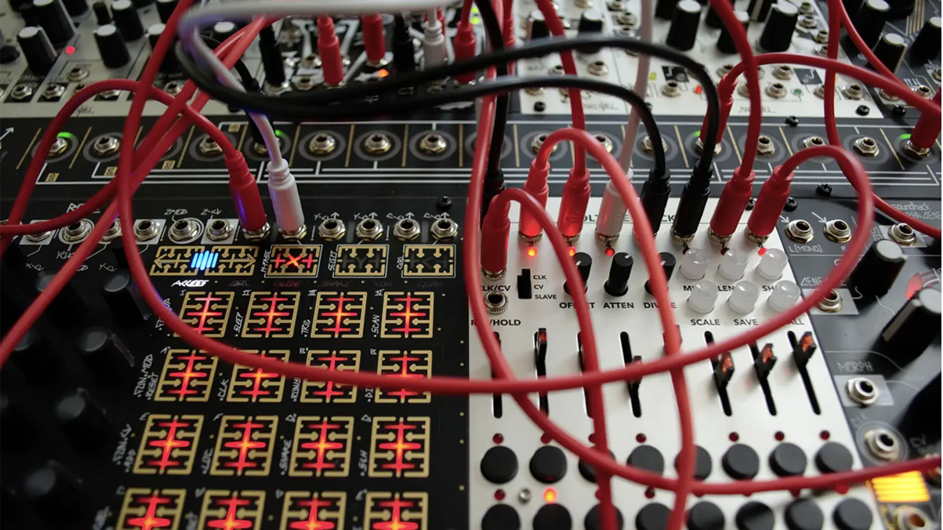 Close up on a professional mixer and soundboard with many red, white, and black crisscrossing wires.