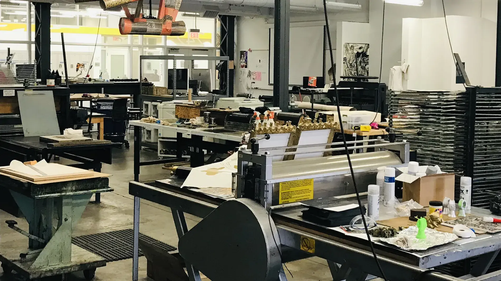 A large well lit room full of tables, huge presses, rollers, drying racks, and copious smaller pieces of equipment.