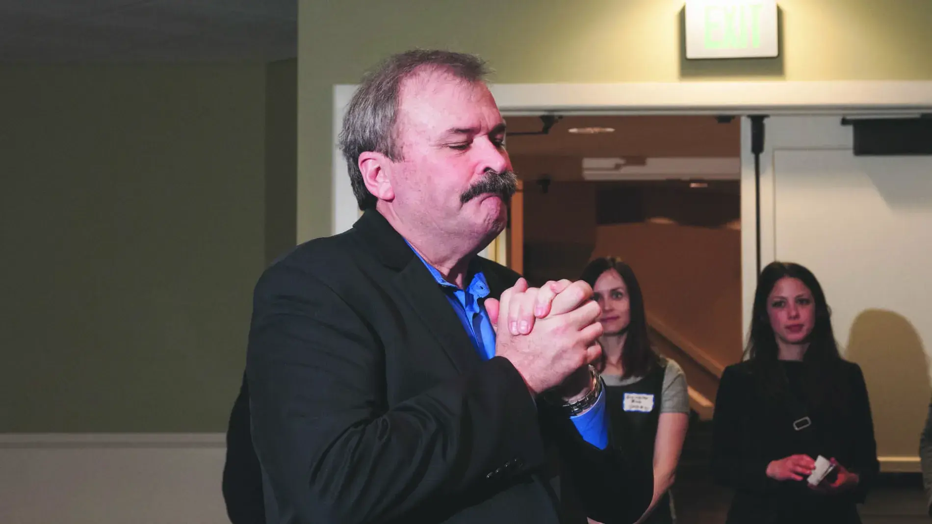 Image of Jim Campbell holding his hands together in gratitude wearing a black suit.