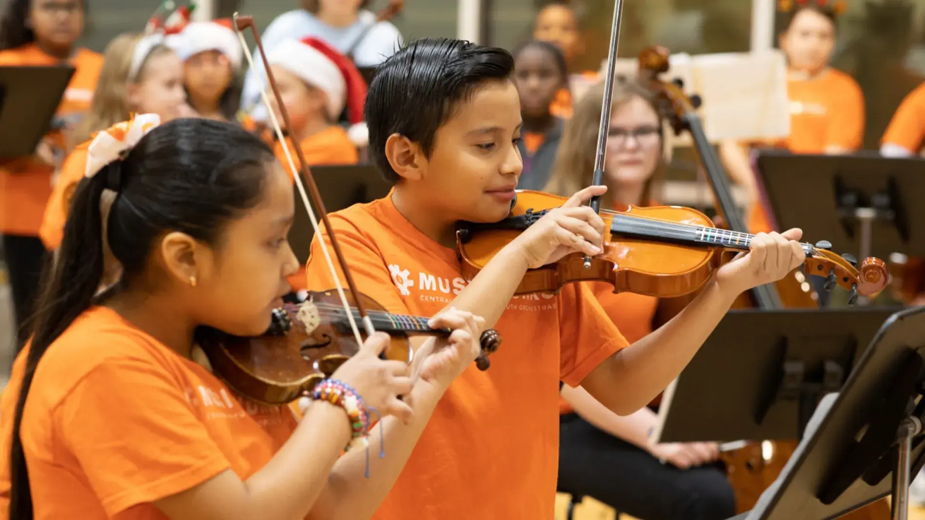 students playing violin in orange shirts