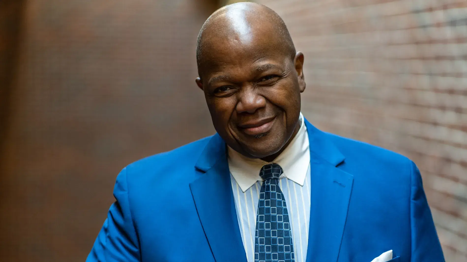 Headshot of Dr. Everett McCorvey wearing a blue suit against a brick wall backdrop