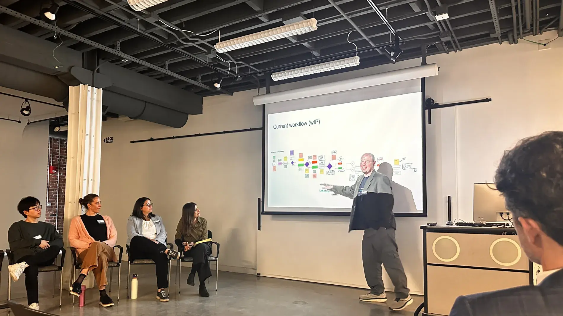 attendees watch a presentation on a projector screen 