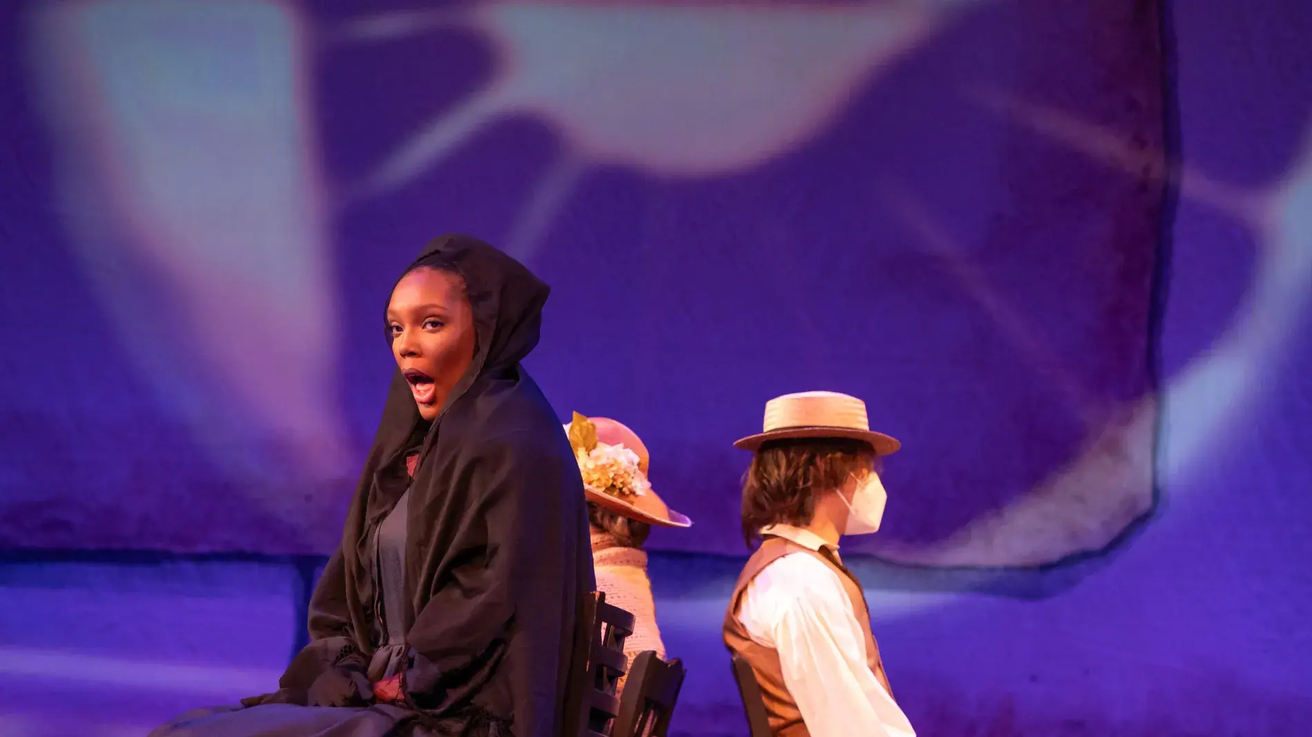 Image of Dejah Watts performing onstage in UK Opera Theatre's "Sanctuary Road" wearing a black dress of mourning