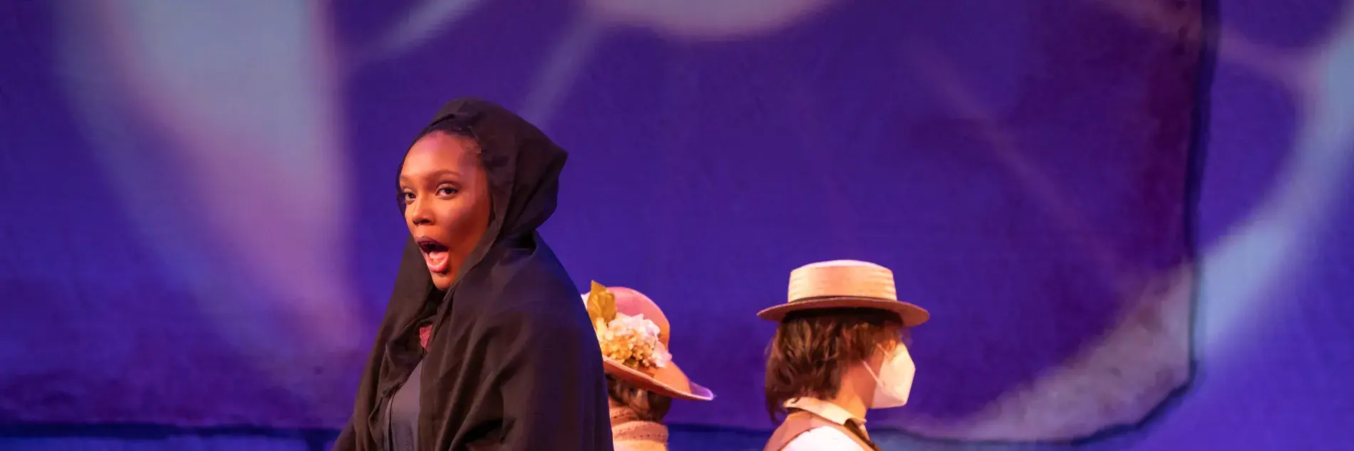 Image of Dejah Watts performing onstage in UK Opera Theatre's "Sanctuary Road" wearing a black dress of mourning