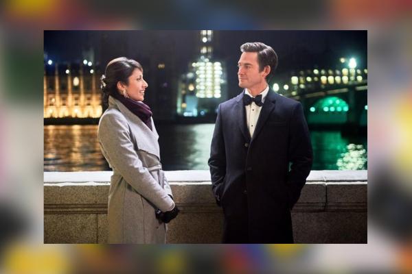 Screenshot of Countdown to Christmas movie, with woman in winter coat and man in tux on a bridge at night