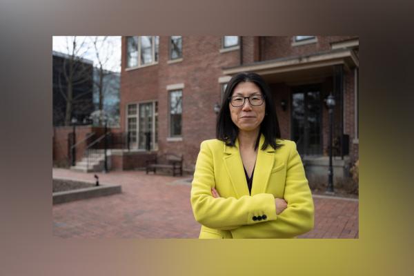 Image of Dr. Yuha Jung in a yellow blazer in front of brick buildings