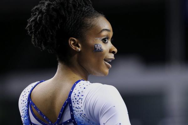 Image of UK student athlete in gymnastics leotard and the UK lockup in facepaint on her cheek