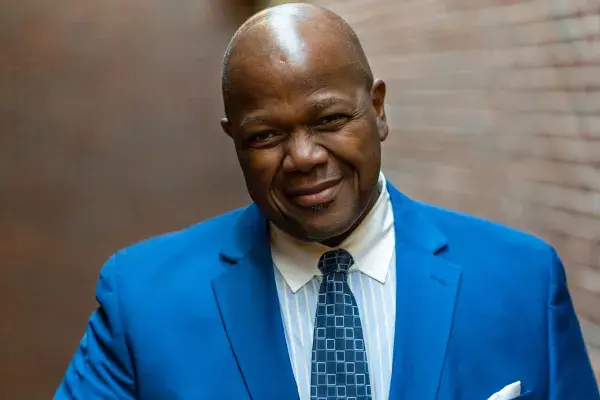 Headshot of Dr. Everett McCorvey wearing a blue suit against a brick wall backdrop