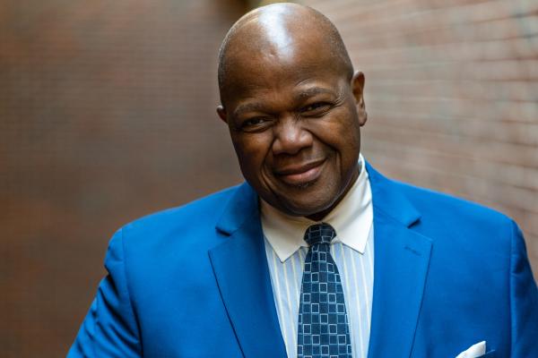Headshot of Dr. Everett McCorvey wearing a blue suit against a brick wall backdrop
